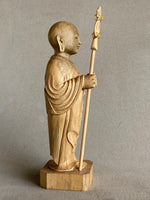 Load image into Gallery viewer, Light colored handcarved wood statue of Jizo as a man, holding a staff with 6 gold rings and in his other hand the Wish Fulfilling Gem, side view
