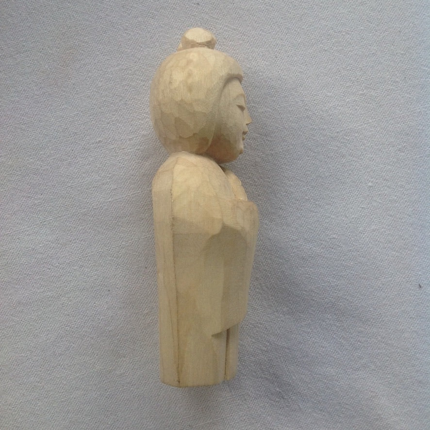 Side view 5 inch tall light colored wood hand carved statue of a Japanese Kuan Yin, knows as Kannon, holding a lotus.