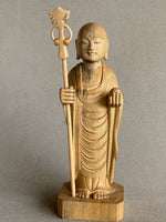 Load image into Gallery viewer, Light colored, with variation in wood color, handcarved wood statue of Jizo as a man, holding a staff with 6 gold rings and in his other hand the Wish Fulfilling Gem.
