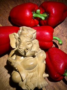 Genesha statue seated with lontar, leaning on red bell peppers.  5 inches tall, hand carved from light colored wood.