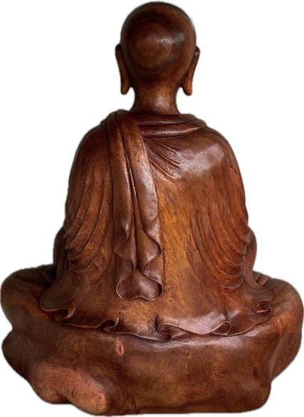 Wooden statue of a seated figure with draped robes on a white background