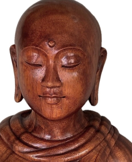 Wooden statue of a Buddhist nun with a serene expression on a white background
