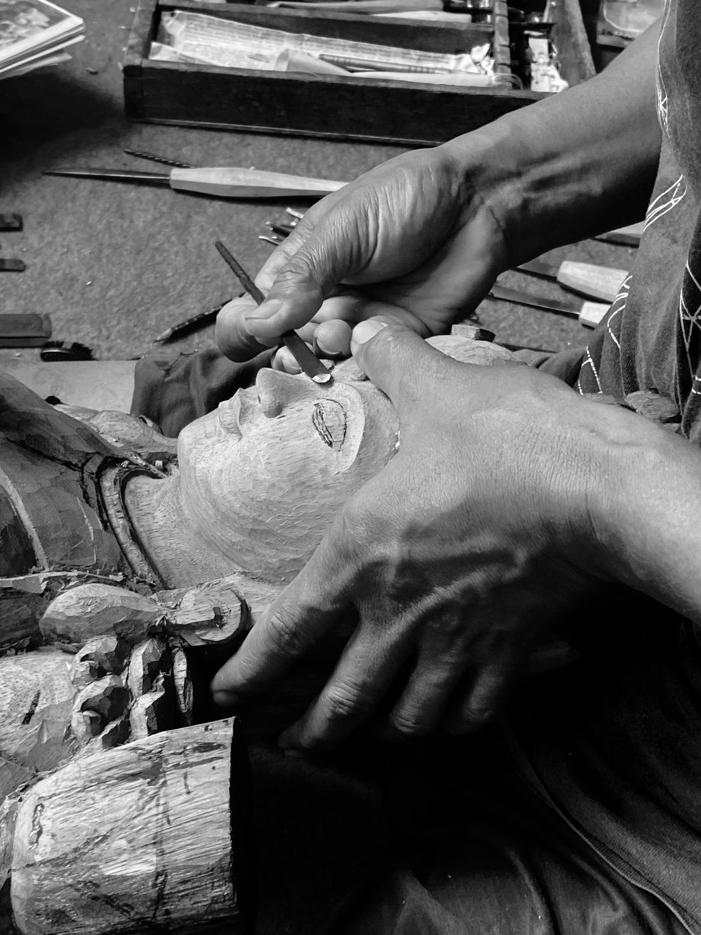 Hands of carver working on face of woman Buddhist wood statue