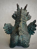 Load image into Gallery viewer, A winged dragon figurine with a textured, weathered green and brown patina finish, shown from the back against a neutral gray background back view.
