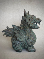 Load image into Gallery viewer, A detailed dragon figurine with a textured green and bronze patina, shown against a neutral textured gray background sideview
