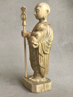 Load image into Gallery viewer, JIzo man standing, holding a staff and a baby, 25cm, 10 inches, color variation in wood from warm light brown to grey grain, 3/4 view.
