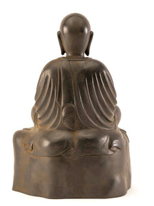 back of Jizo in Meditation serenely seated on a rock warm rust brown