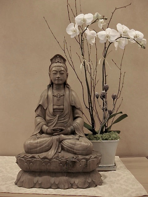 Quan Yin Statue Seated on Double Lotus original on altar at Spirit Rock Meditation Center with white orchids behind.